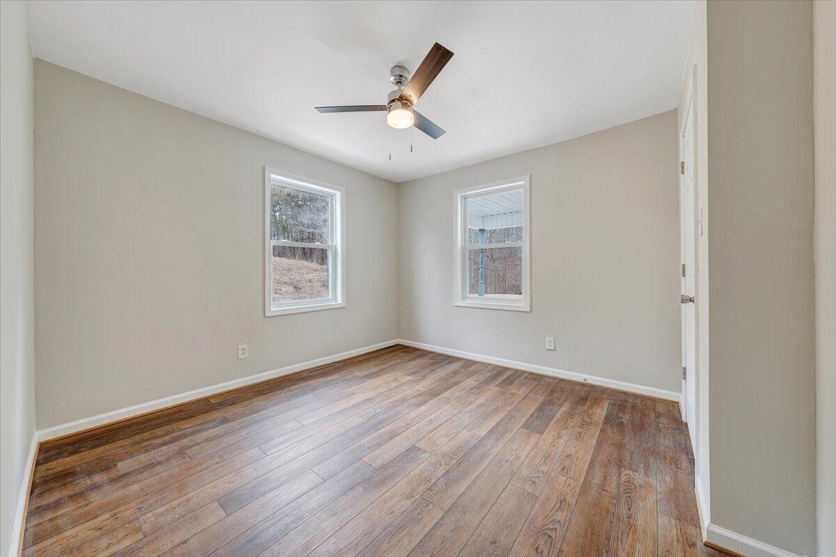 4160 Prillaman Switch Road Ferrum, VA 24088 - Photo 16 of 41 an empty room with wooden floor ceiling fan and windows