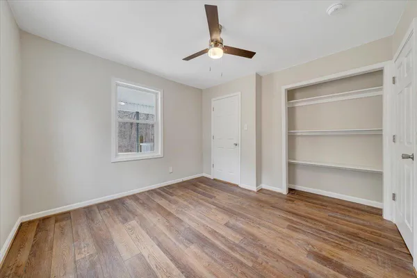 a view of empty room with wooden floor and fan