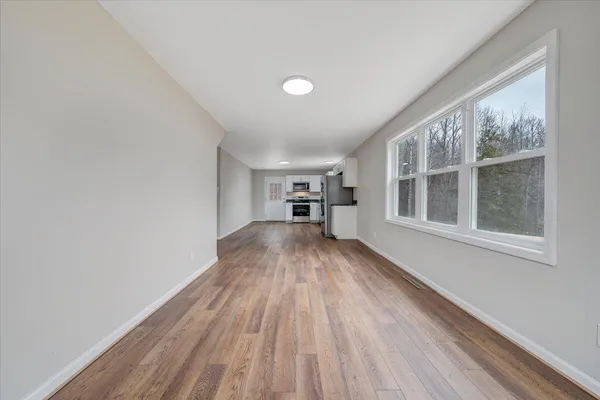 a view of empty room with wooden floor and windows