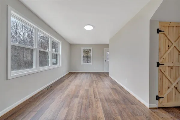a view of an empty room with wooden floor and a window