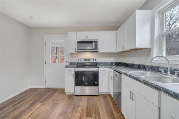 a kitchen with granite countertop a stove a sink and a microwave