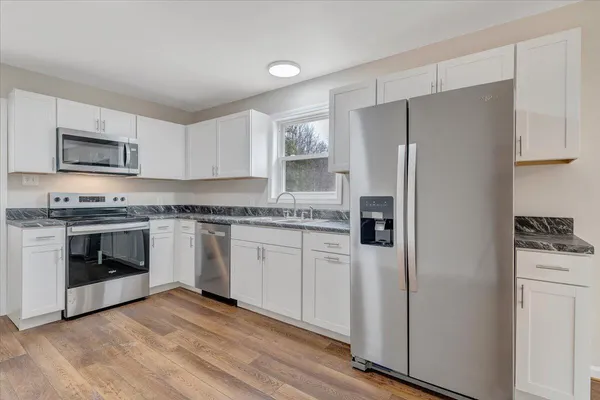 a kitchen with granite countertop cabinets stainless steel appliances and a refrigerator