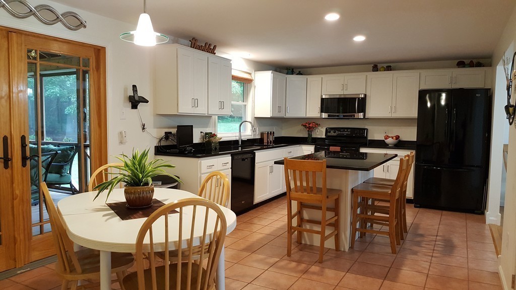 23 Calvin Street Ayer, MA 01432 - Photo 9 of 30 a kitchen with stainless steel appliances kitchen island granite countertop a sink a stove a dining table and chairs