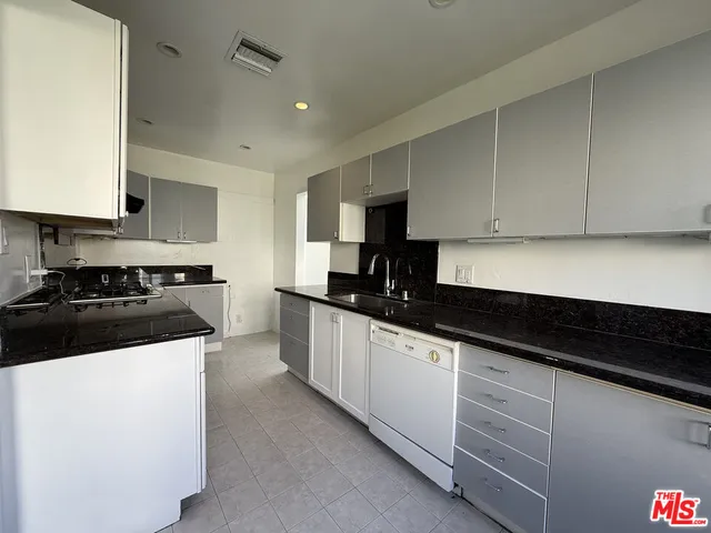 a kitchen with granite countertop white cabinets and black appliances