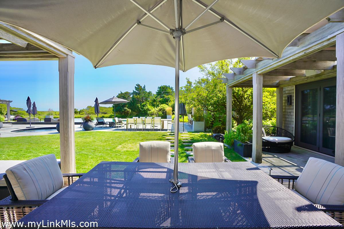 30 Crackatuxet Road Edgartown, MA 02539 - Photo 41 of 45 a view of a patio with chairs and a table under an umbrella