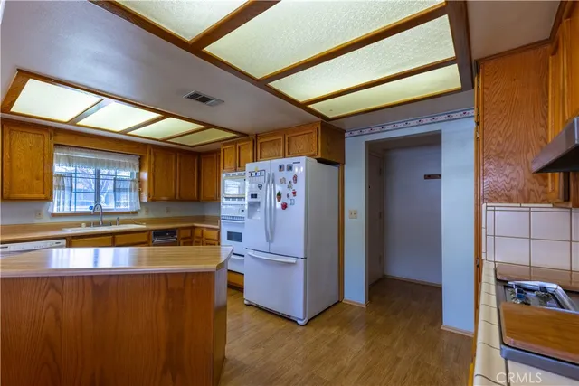a kitchen with stainless steel appliances granite countertop a refrigerator a stove and a wooden cabinets