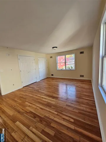 a view of empty room with window and wooden floor