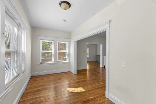 a view of an empty room with wooden floor and a window