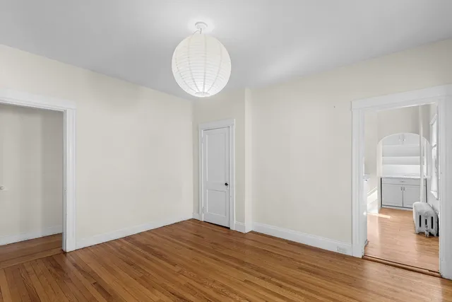 a view of empty room with wooden floor and bathroom