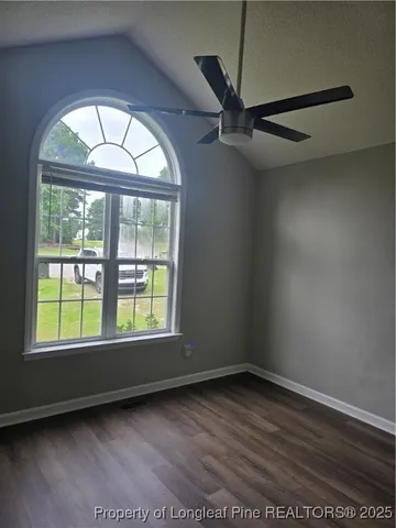 an empty room with wooden floor cabinet and windows