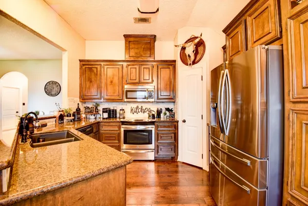 a kitchen with stainless steel appliances granite countertop a refrigerator a stove and a sink with wooden floor