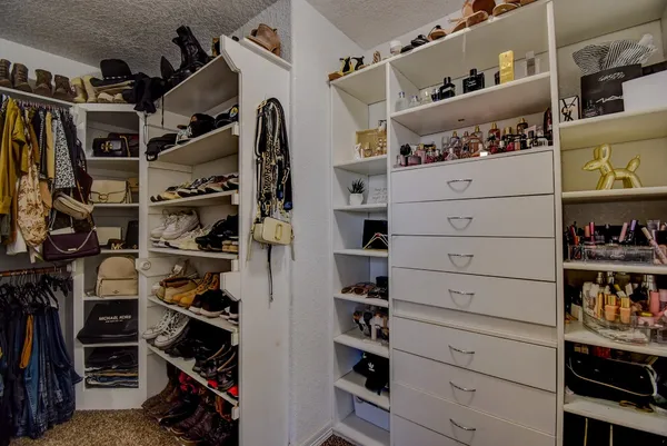 a view of walk in closet with clothes and shoes