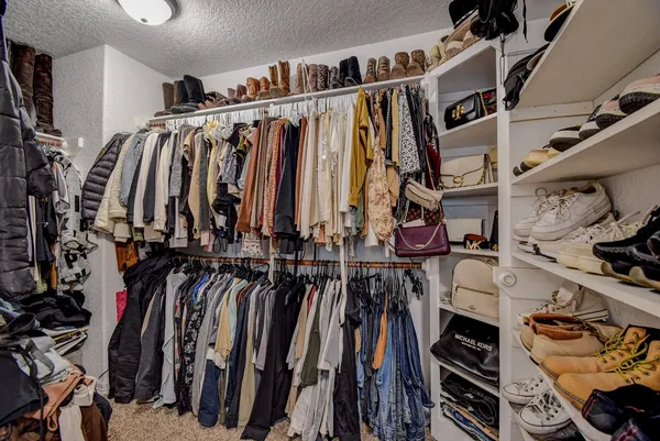 a view of walk in closet with clothes and shoes