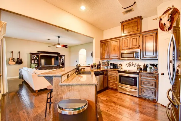 a kitchen with stainless steel appliances a stove a sink dishwasher and a refrigerator with wooden floor