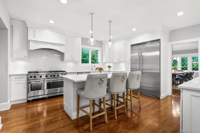 a kitchen with stainless steel appliances a table chairs stove and wooden floor