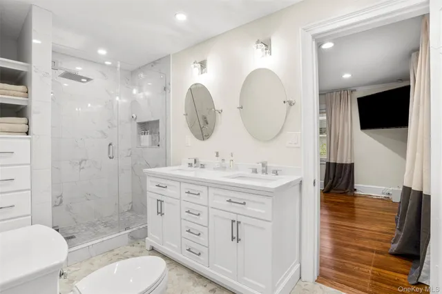 a bathroom with a toilet a sink a shower a mirror and vanity