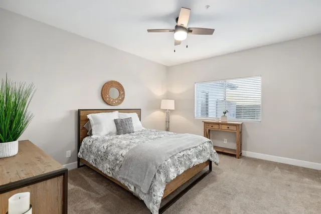 a bedroom with a bed and a potted plant on the dresser