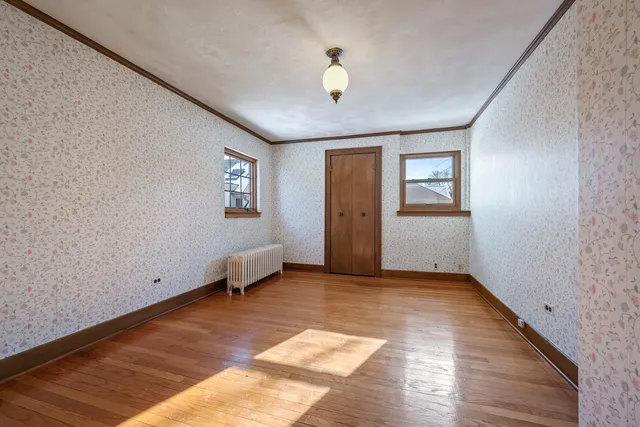 a view of an empty room with window and wooden floor