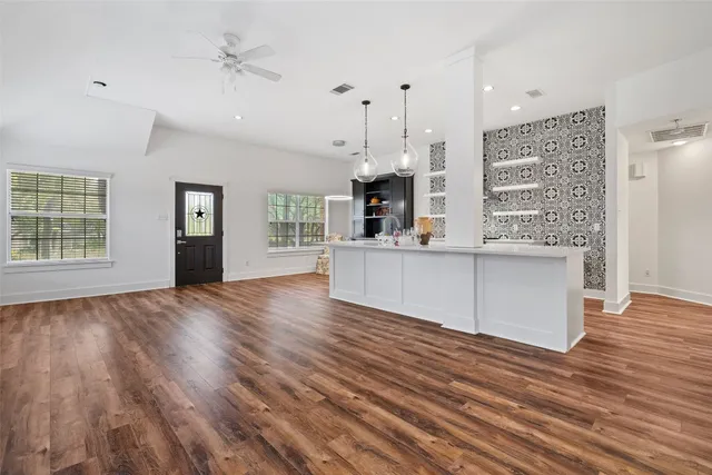 a view of an empty room with window and wooden floor
