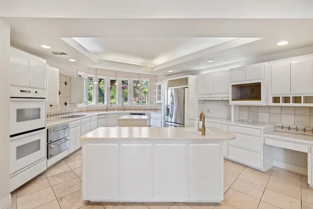 a kitchen with kitchen island white cabinets appliances and a counter top space