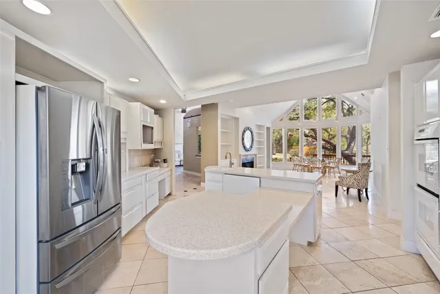a large white kitchen with stainless steel appliances granite countertop a refrigerator and a sink