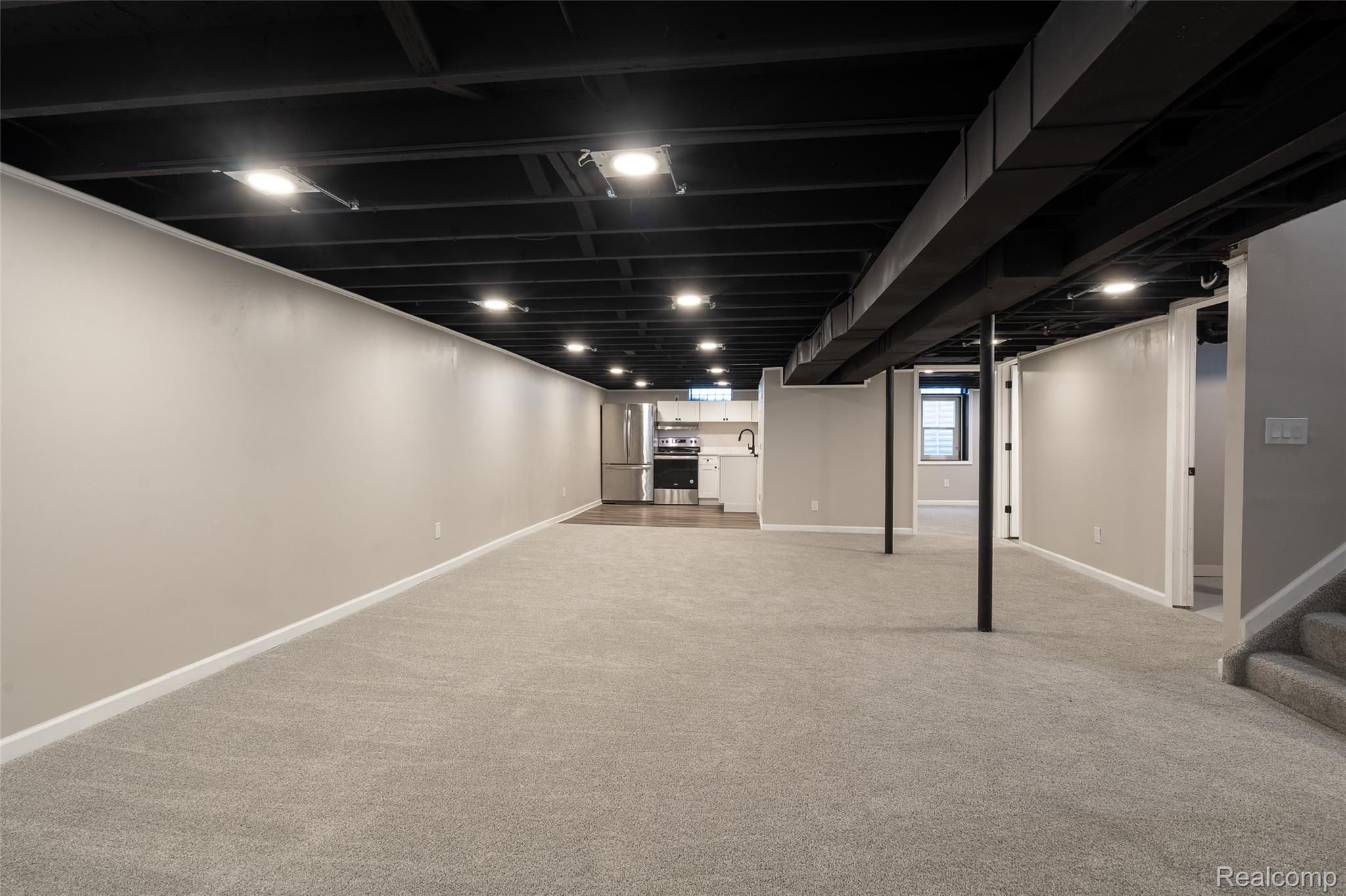 201 Cardwell Street Inkster, MI 48141 - Photo 31 of 41 Open-concept lower level featuring recessed lighting, painted exposed ceiling joists, light gray carpeting, and a built-in kitchenette with stainless steel appliances