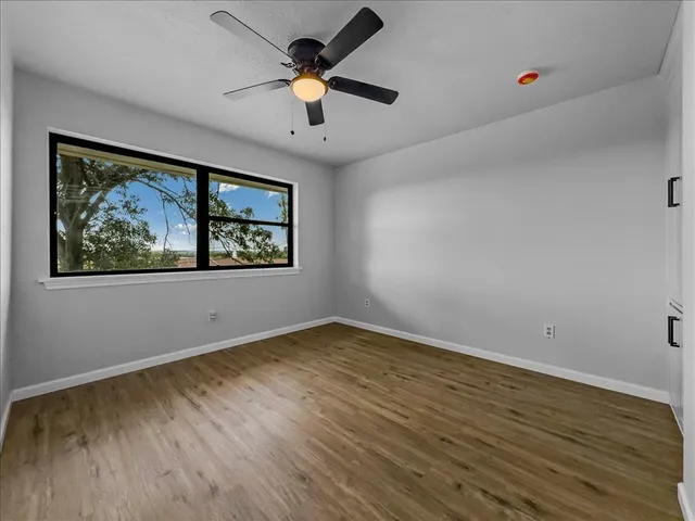 a view of an empty room with a window and wooden floor