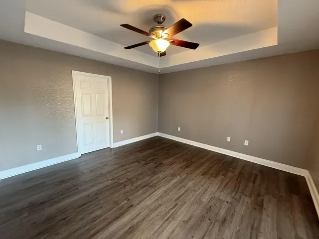 an empty room with wooden floor and ceiling fan