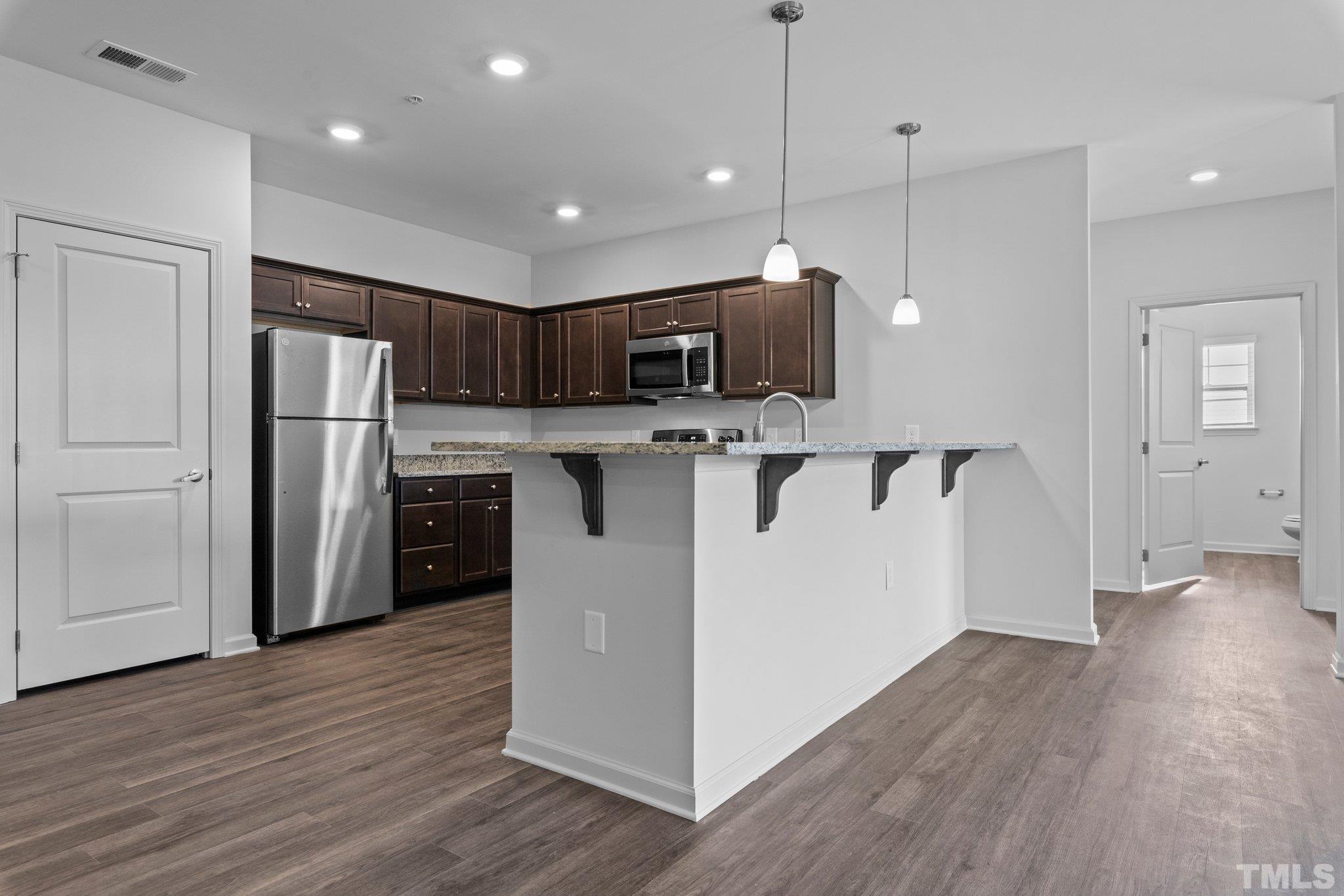 a kitchen with kitchen island a sink stainless steel appliances and wooden floor