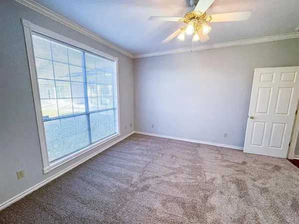 an empty room with chandelier fan and windows