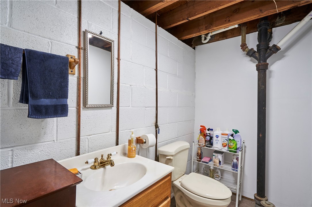15813 Wingate Road Maple Heights, OH 44137 - Photo 17 of 26 Half bath with toilet, vanity, and concrete block wall