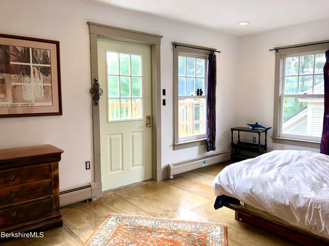 a spacious bedroom with a bed and wooden floor