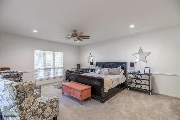 a spacious bedroom with a bed a couch and windows