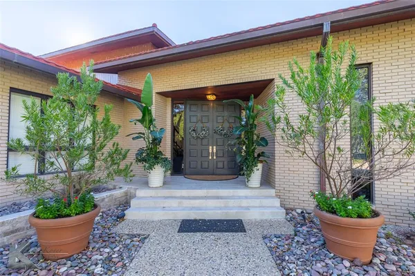 a view of a entryway door of the house with potted plants