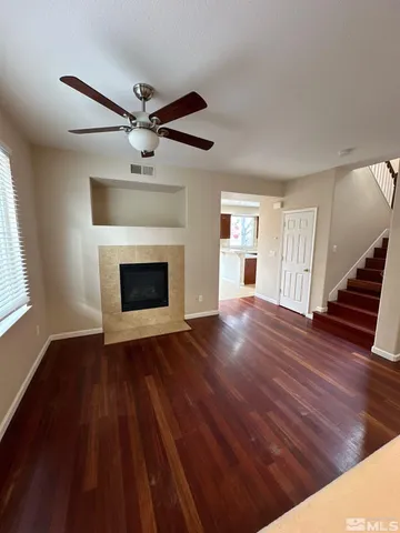 a view of an empty room with wooden floor fireplace and a window