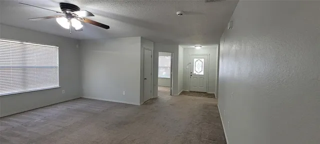 an empty room with windows and fan