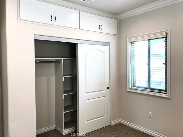 a view of an empty room with closet and a window