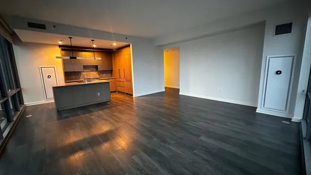 a view of a big room with wooden floor and windows