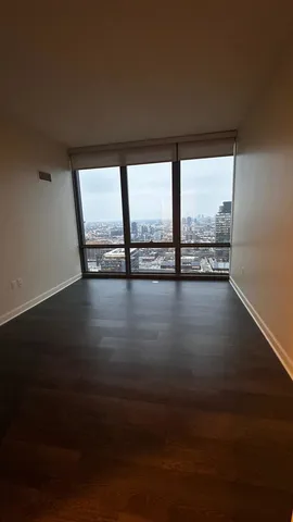 a view of an empty room with wooden floor and a floor to ceiling window