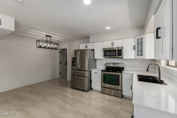 a kitchen with granite countertop a refrigerator and a stove top oven