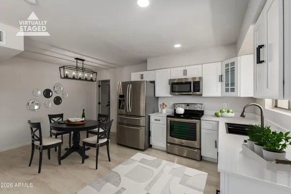 a kitchen with stainless steel appliances a table chairs microwave and refrigerator