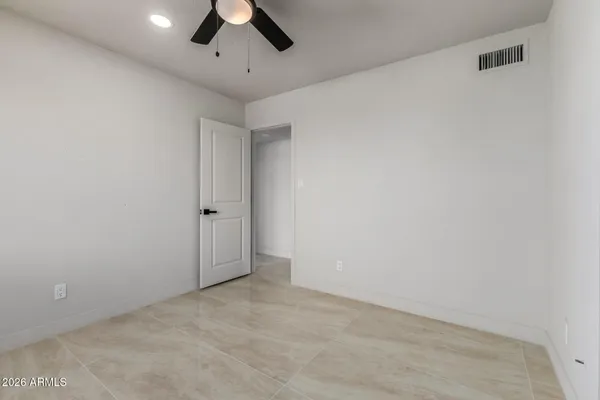 an empty room with a ceiling fan and carpet