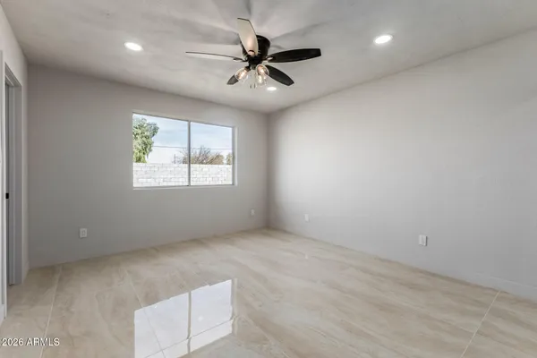 an empty room with windows and ceiling fan