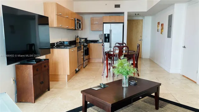 a kitchen with stainless steel appliances granite countertop a dining table chairs refrigerator and microwave