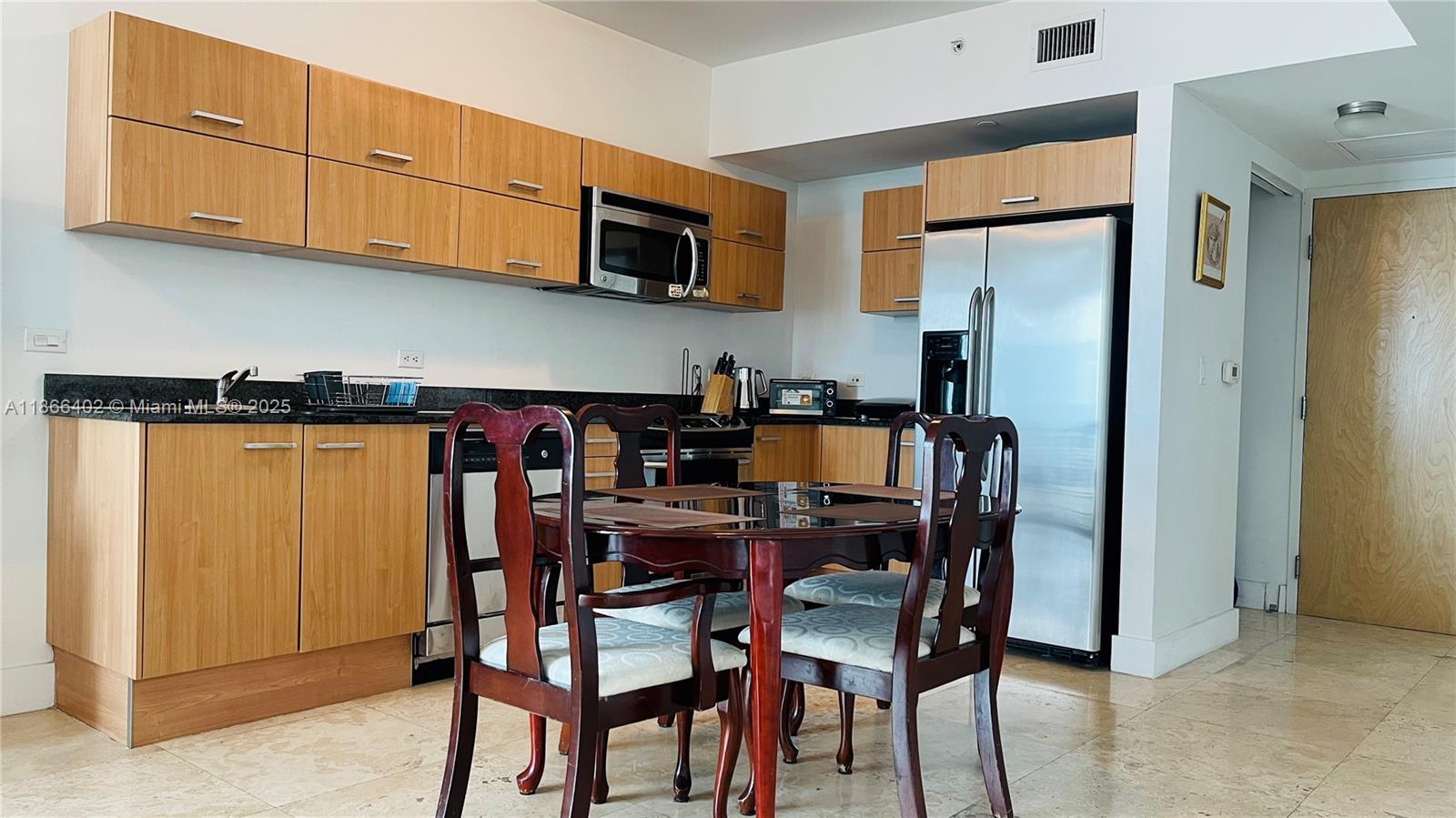 350 South Miami Avenue, Unit 2611 Miami, FL 33130 - Photo 6 of 34 a kitchen with stainless steel appliances granite countertop a dining table chairs refrigerator and microwave