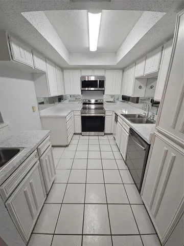 a kitchen with granite countertop white cabinets a sink dishwasher and a stove top oven