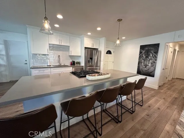 a kitchen with stainless steel appliances kitchen island granite countertop a dining table chairs and a refrigerator