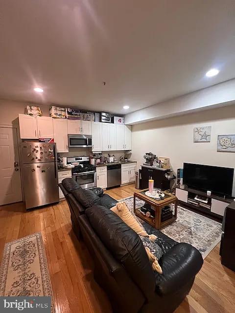 a living room with stainless steel appliances furniture and a flat screen tv