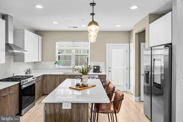 a kitchen with stainless steel appliances granite countertop a sink a stove a refrigerator cabinets a dining table and chairs
