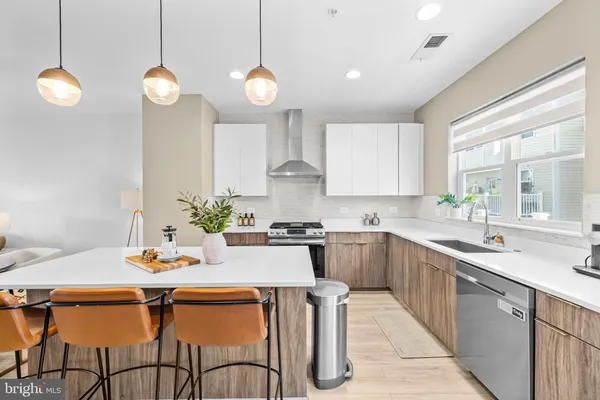 a kitchen with stainless steel appliances kitchen island granite countertop a sink a stove a dining table and chairs